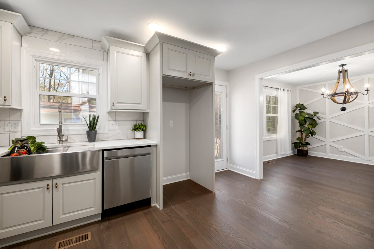 Bright modern kitchen featuring stainless steel sink and appliances with wooden flooring.