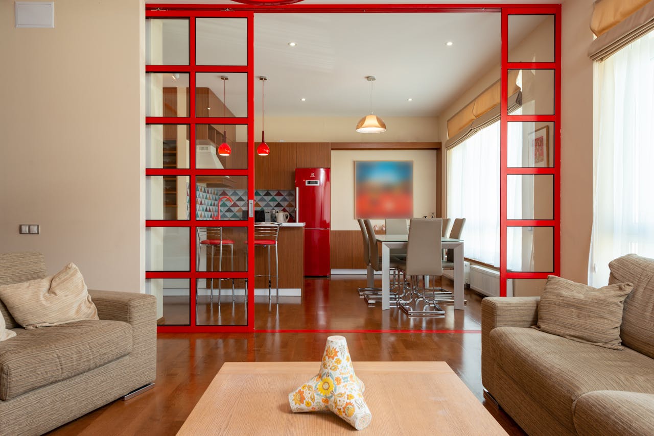 Spacious modern living room with red-framed kitchen divider and stylish furnishings.